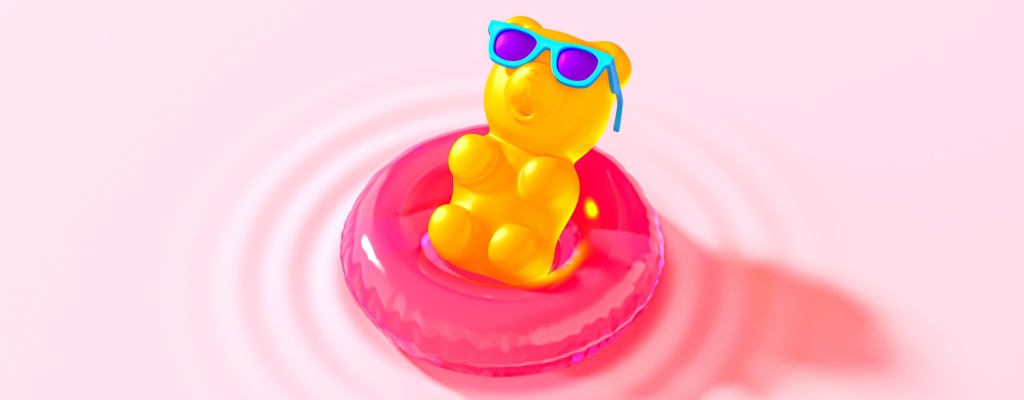 A gummy bear wearing sunglasses and sitting on an inner tube relaxes in a pink pool. 
